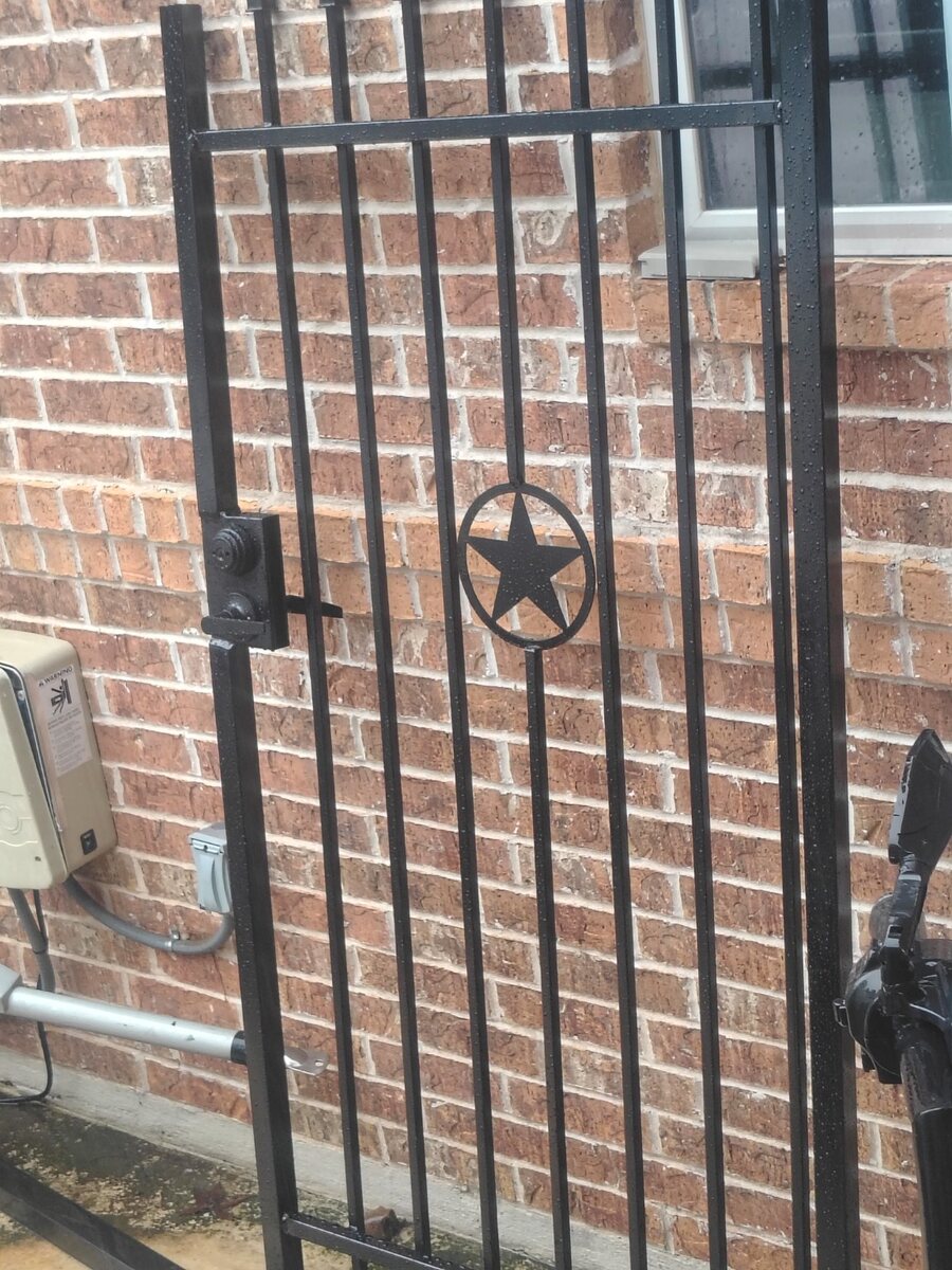 Custom iron gate installation next to brick home